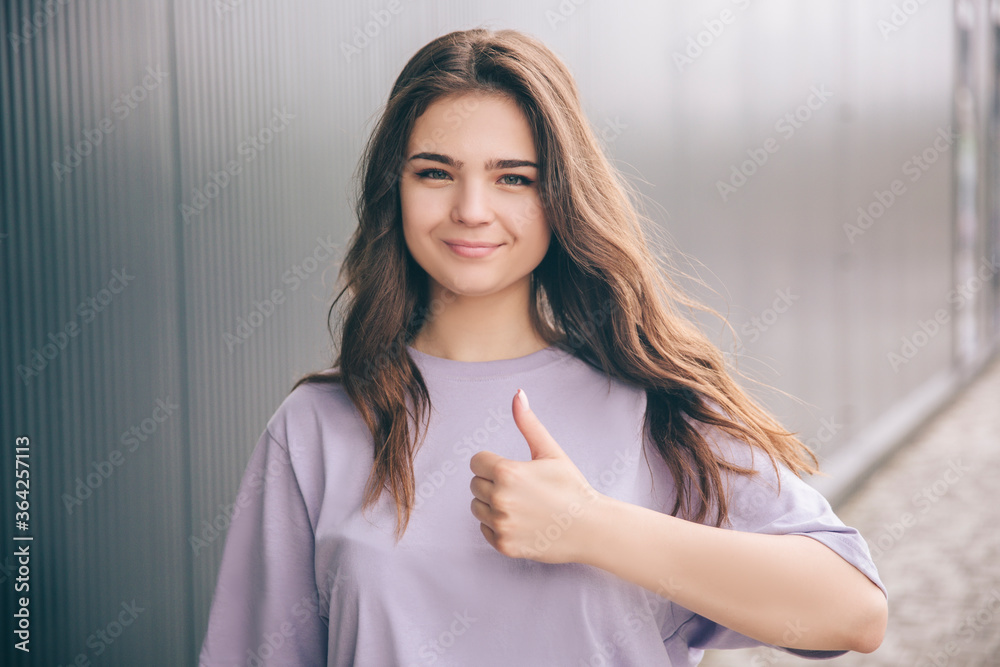 Young stylish trendy woman isolated over grey blue background. Positive beautiful girl holding big thumb up and smile. Posing on camera. Like sign or symbol. Young stylish trendy woman isolated over grey blue background. Positive beautiful girl holding big thumb up and smile. Posing on camera. Like sign or symbol.