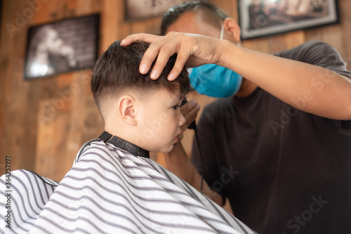 little boy hair with an electric clipper, in barber shop