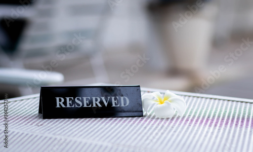 Reserved metal black plate in a restaurant. Reserved metal plate On the white table. vintage photo processing. close up of a setting a reserved sign on the restaurant table.