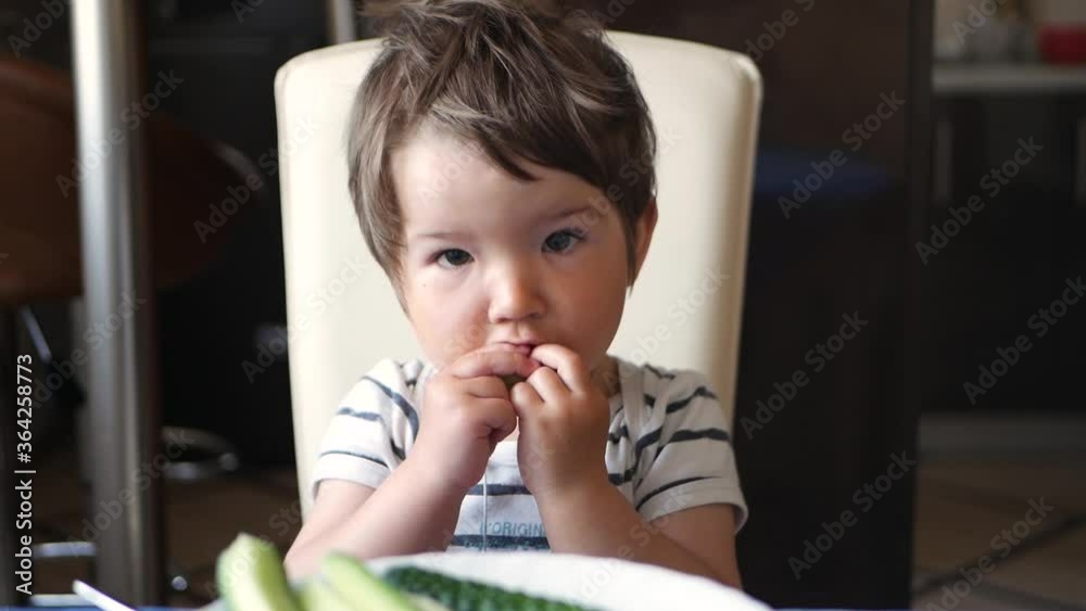 Child eating sliced cucumbers at the table of the house Child eating sliced cucumbers at the table of the house