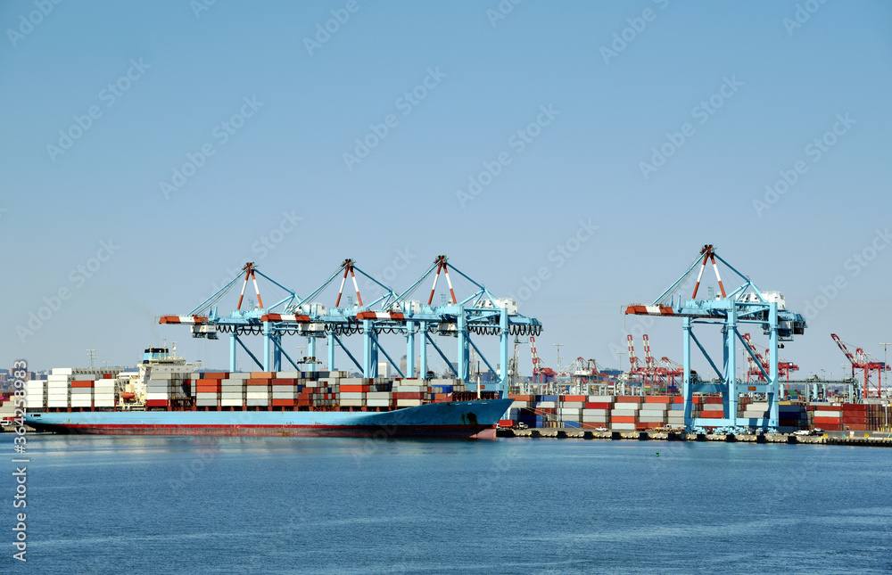 Newark, NJ / USA - View of the container terminal with berthed ship, gantry cranes are loading and discharging cargo from the vessel.