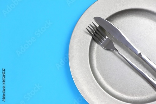 Fork and knife on a plate. Top view, flat lay, copy space.