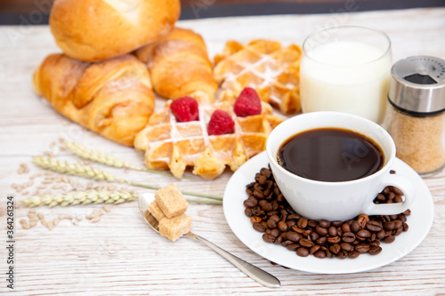 Breakfast in the morning with black coffee cup with bread with Croissant and fruit on the wooden table.