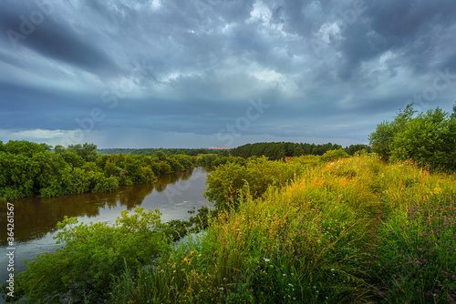 Summer landscape with river and storm clouds