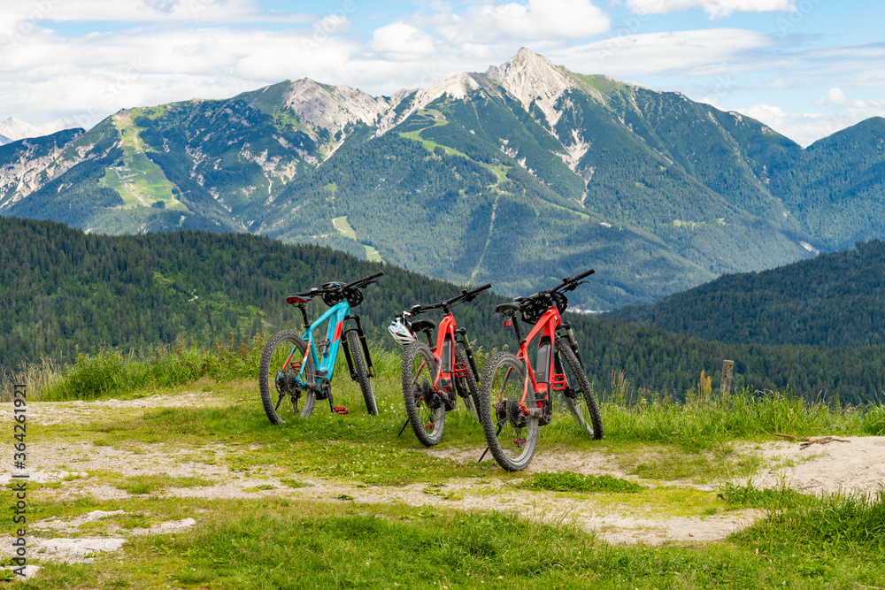 three electric mountain bikes in the alps and in the background mountains and a beautiful view