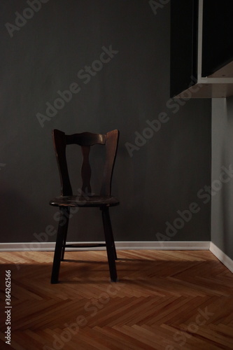 Fototapeta Naklejka Na Ścianę i Meble -  Vintage wooden chair in dark grey room with classic timber parquet floor in the ray of light