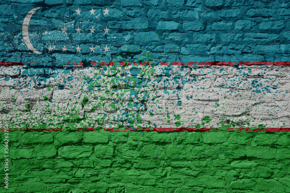 Fototapeta premium painted big national flag of uzbekistan on a massive old brick wall