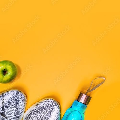 Flat lay composition with fitness equipment and space for text on yellow color background. healthy and active lifestyle love concept sport sneakers, bottle of water apple. Copy space