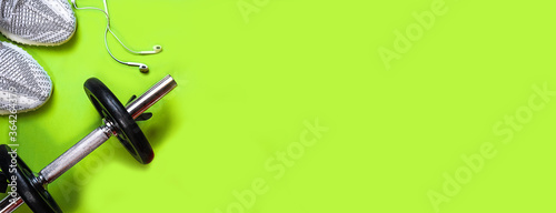 Top view dumbbell, sport sneakers tennis racquet headphones on bright green background. Layout with fitness equipment and space for text. healthy and active lifestyle. Copy space, flat lay horizontal