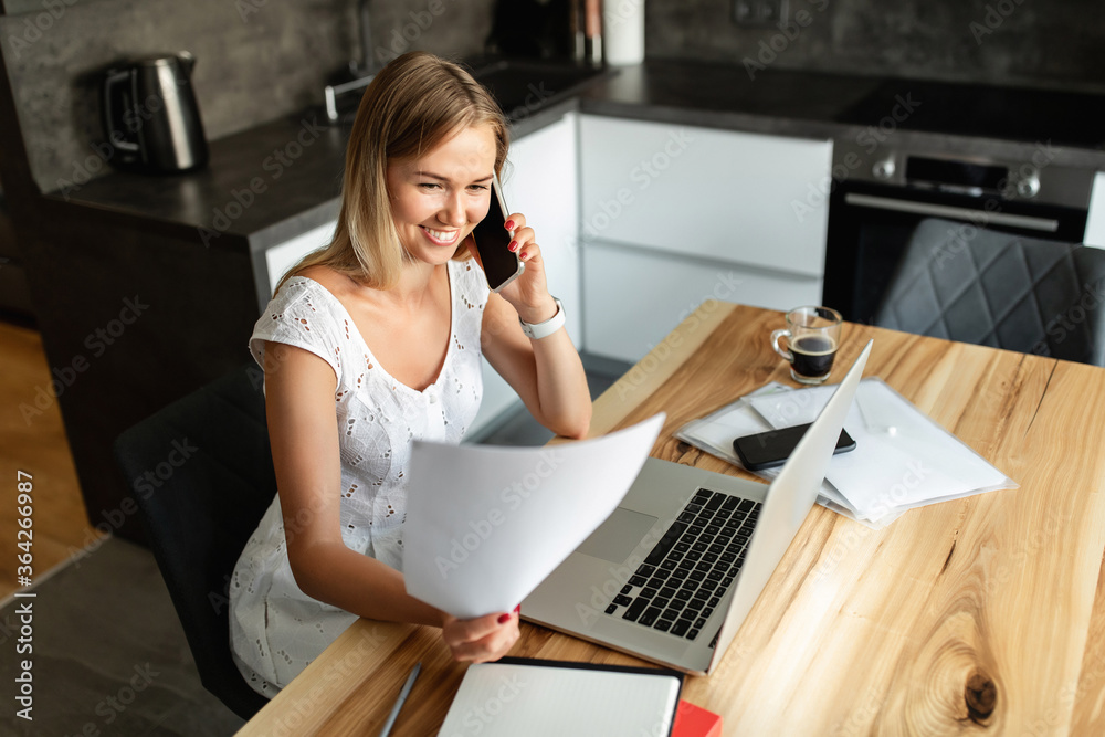 Woman with smartphone working on laptop at home office Woman with smartphone working on laptop at home office