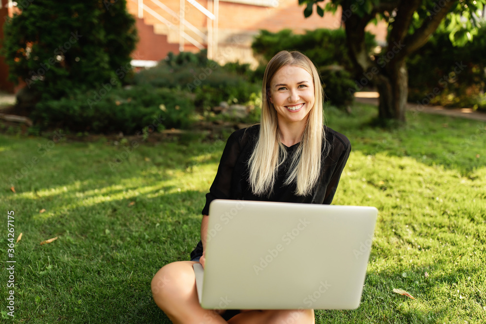 Work outdoors. Woman sitting in the park with laptop and working.