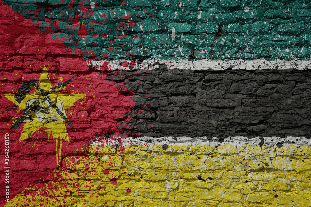 Fototapeta premium painted big national flag of mozambique on a massive old brick wall