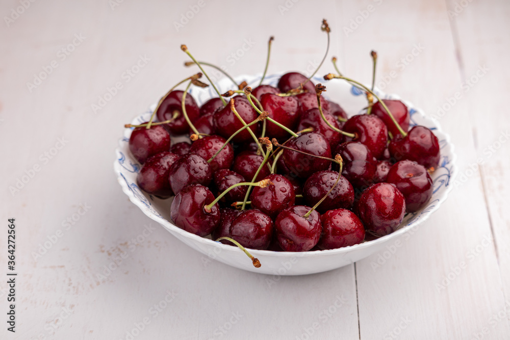 sweet cherries in a bowl on a wooden background
