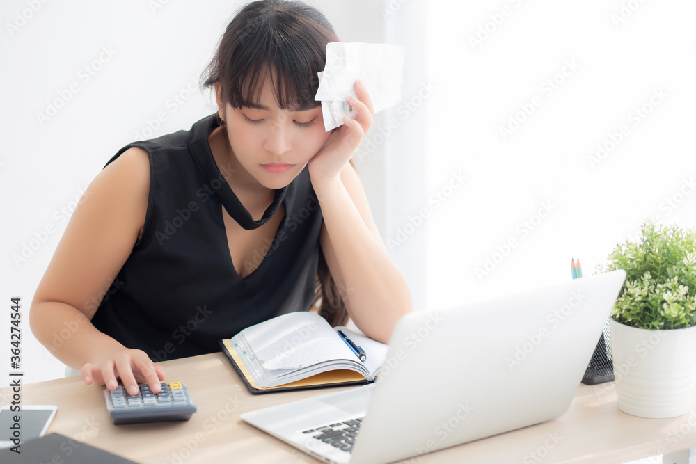 Beautiful young asian woman calculating expenses household and writing notebook on desk, girl checking bill and stress and note, female worry debt and tax, finance and business concept. Beautiful young asian woman calculating expenses household and writing notebook on desk, girl checking bill and stress and note, female worry debt and tax, finance and business concept.