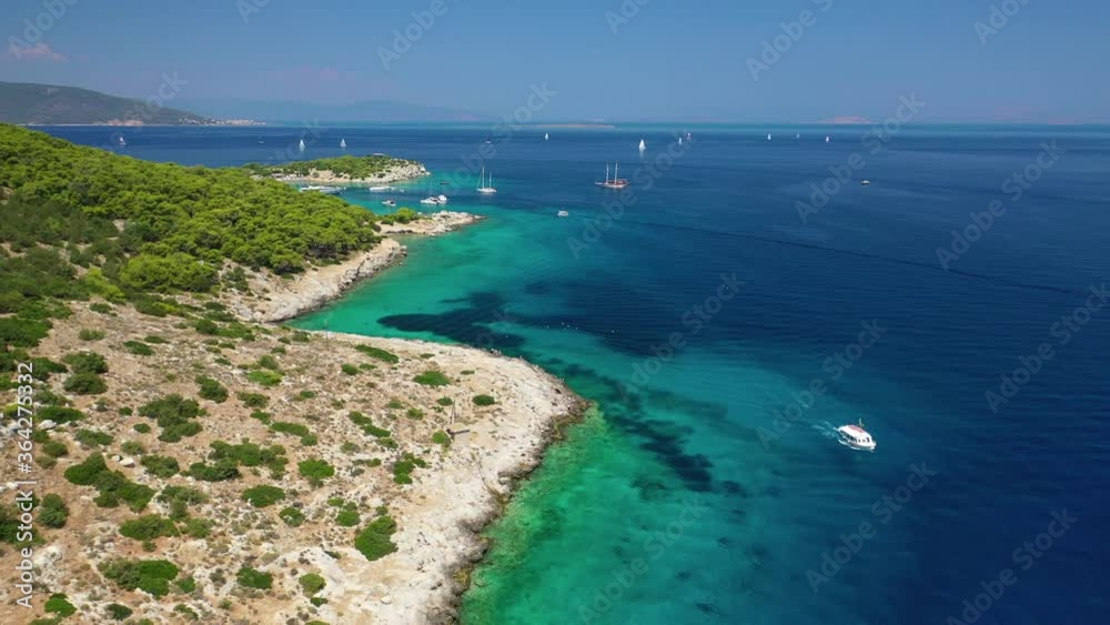 Aerial drone video of small tropical Caribbean island with beautiful turquoise and sapphire clear sea covered with pine trees