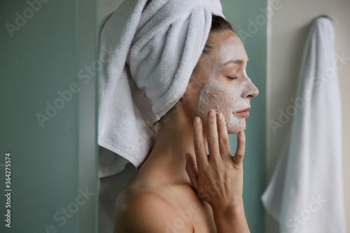фотографія Young woman in bathroom wrapped in towels with facial mask