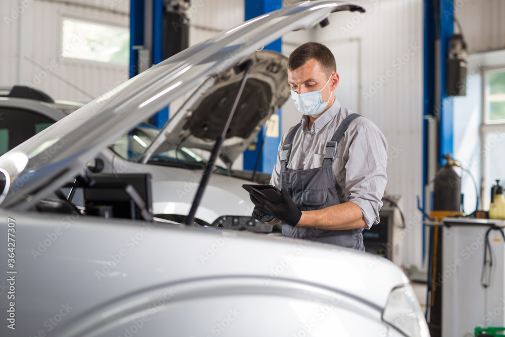 car service worker carries out diagnostics and car repairs in the room. car service worker carries out diagnostics and car repairs in the room.
