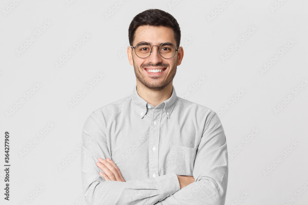 Smiling handsome man in shirt and round glasses standing with crossed arms isolated on gray Smiling handsome man in shirt and round glasses standing with crossed arms isolated on gray