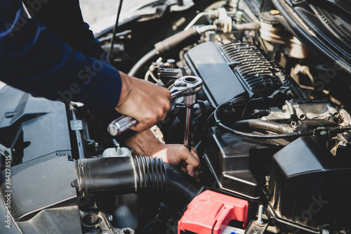 Auto mechanic hands using wrench to repair a car engine. concepts of car care fix repair service and insurance.