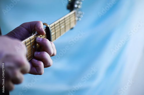 An acoustic guitar for an artist playing a stringed musical instrument on stage. Black guitar with a capo. Musical background.