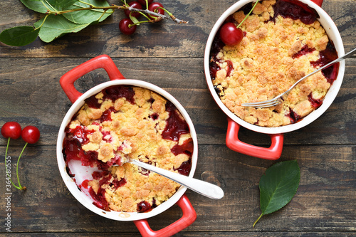 Homemade crumble with cherries and nuts on a wooden background. View from above. photo