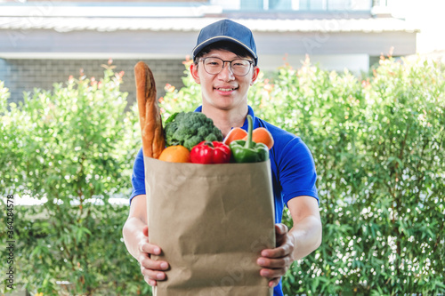 Food Delivery concept. Asian delivery man hand giving bag of food, fruit, vegetable delivery to costomer grocery delivery service. photo