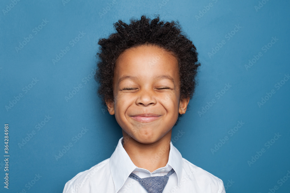 Happy black child boy maks a wish on blue background Happy black child boy maks a wish on blue background