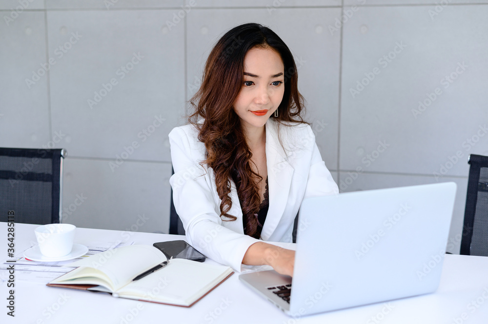 Portrait of a attractive young businesswoman working on a laptop in her workstation Portrait of a attractive young businesswoman working on a laptop in her workstation
