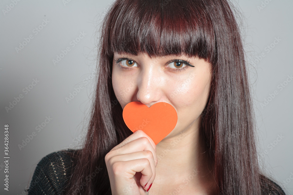 Woman is holding paper heart in front of her mouth Woman is holding paper heart in front of her mouth