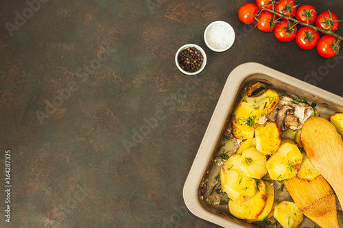 Potato wedges baked with mushrooms, herb oven roasted, with thyme, a close-up in a baking tray photo