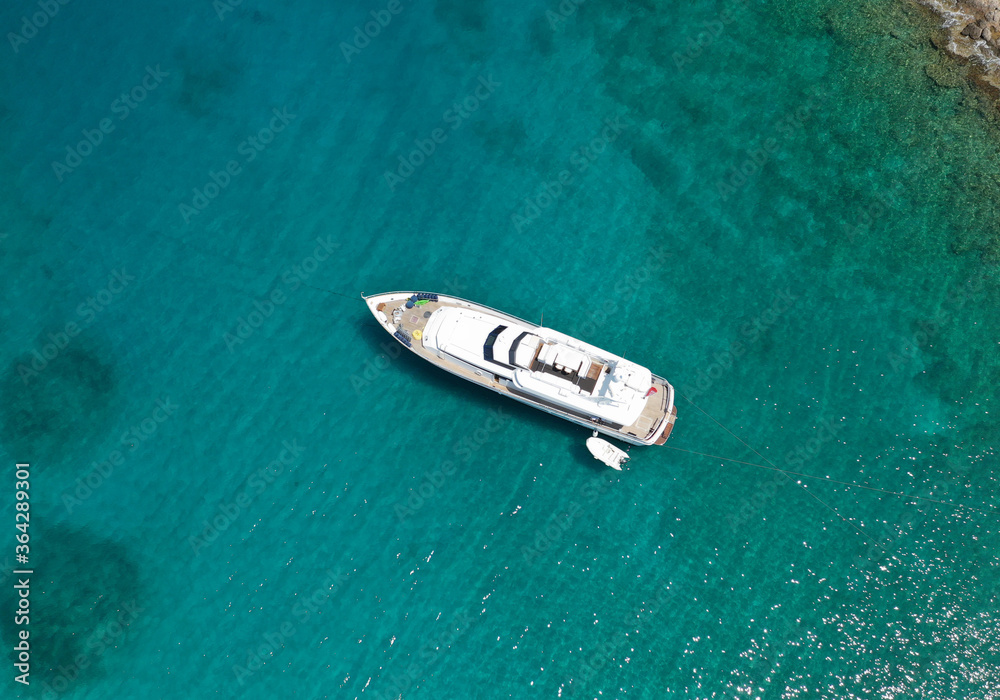 Aerial drone photo of yacht - boat with wooden deck anchored in tropical exotic paradise with turquoise open sea Aerial drone photo of yacht - boat with wooden deck anchored in tropical exotic paradise with turquoise open sea