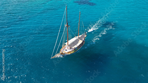 Aerial drone photo of beautiful wooden deck classic sailing yacht cruising in open ocean deep blue sea