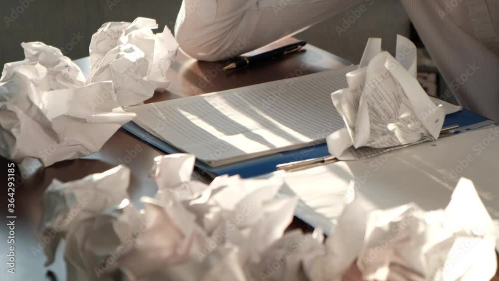 Unrecognizable nervous businessman angrily sweeps everything from the desktop and crumpled paper