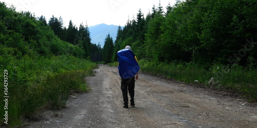 Man walking on a forest road. Trekking journey and travel concept