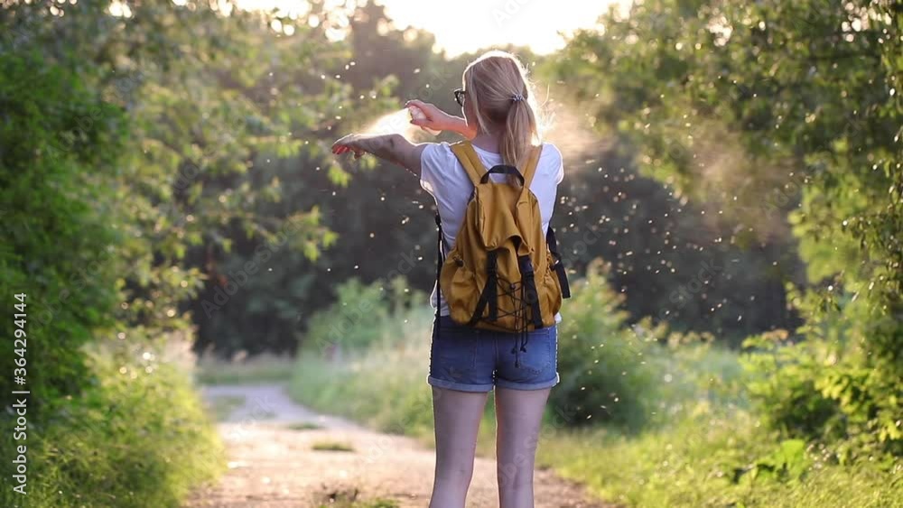 Skin care in nature. Woman applying insect repellent against mosquito and tick on her hands and legs during hike outdoors. Skin protection against insect bite