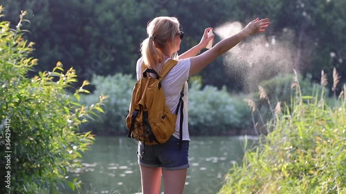 Woman applying insect repellent against mosquito and tick on her hands and legs during hike outdoors. Skin protection against insect bite. Skin care in nature