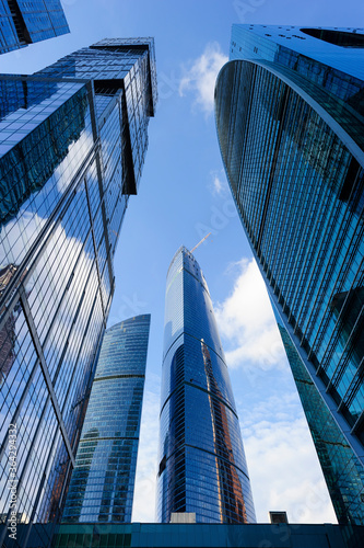 Modern business office skyscrapers, looking up at high-rise buildings in commercial district, architecture raising to the blue sky with white clouds, bottom view