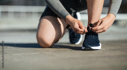 Morning running. Young man tying shoelaces on sneakers, on track