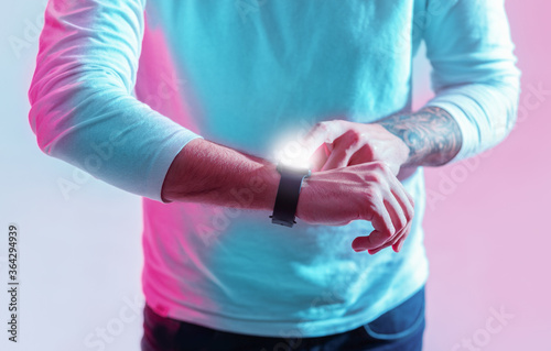 New generation and devices. Guy controls smart watch in neon