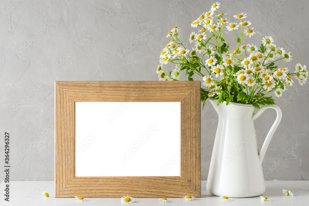 White chamomile flowers bouquet with blank photo frame on white background. mock up. still life White chamomile flowers bouquet with blank photo frame on white background. mock up. still life