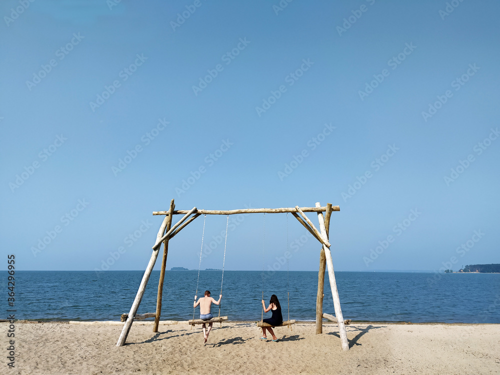 Loving married couple swinging on a swing on the beach. Siberia. Russia. Ob. Mobile photo. July, 12. 2020 Loving married couple swinging on a swing on the beach. Siberia. Russia. Ob. Mobile photo. July, 12. 2020