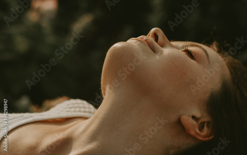 Close up portrait of neck and chin area with skin details, of a young woman relaxing in the park