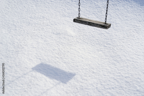 Empty swing in winter time with snow