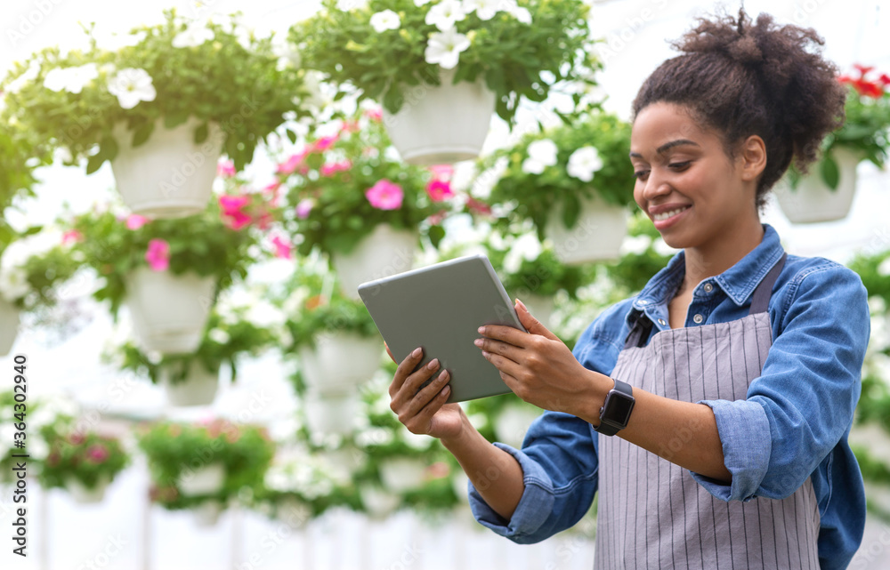 Smart greenhouse with digital control. Smiling african american girl with tablet in hands Smart greenhouse with digital control. Smiling african american girl with tablet in hands