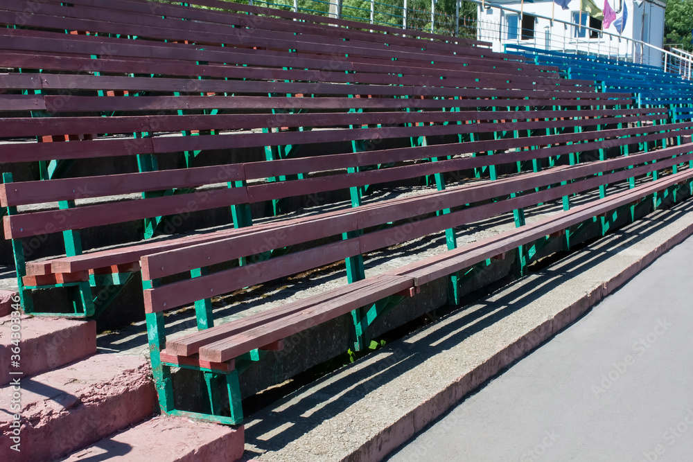 old wooden benches of different colors in a provincial stadium