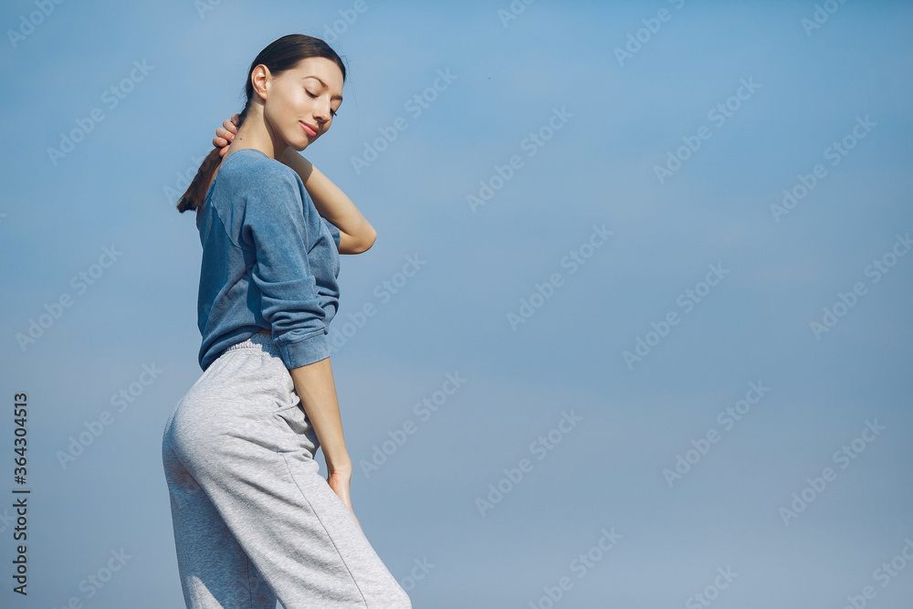 Beautiful girl training on a sky background. Woman in a blue sweater. Lady make a yoga Beautiful girl training on a sky background. Woman in a blue sweater. Lady make a yoga