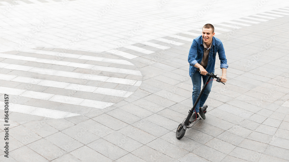 Happy guy having pleasant ride on electric kick scooter Happy guy having pleasant ride on electric kick scooter