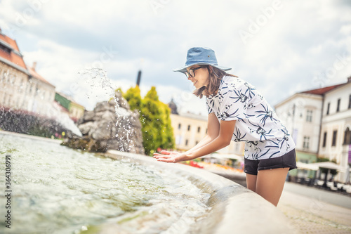 Teenage girl refreshing in a fountain on a hot summer day in the city