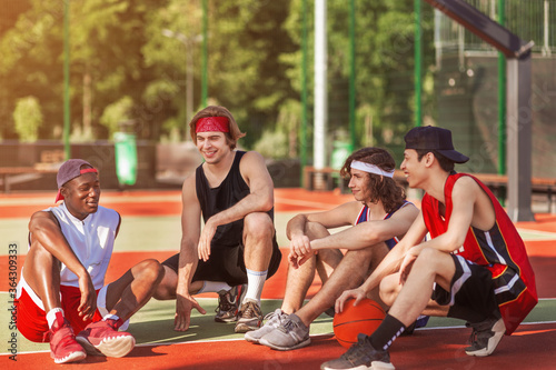 Multiracial basketball players relaxing after game at outdoor court © Prostock-studio