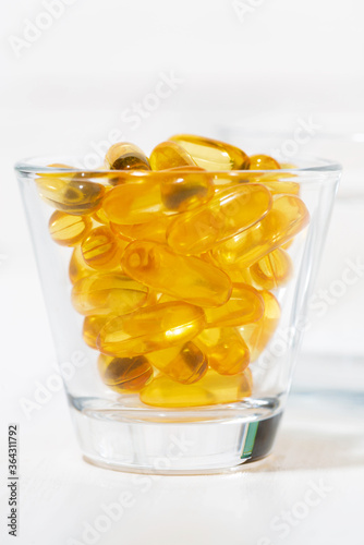 dietary supplement - fish oil capsules in a glass, vertical photo
